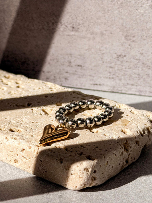 Silver beaded ring with gold heart charm on stone