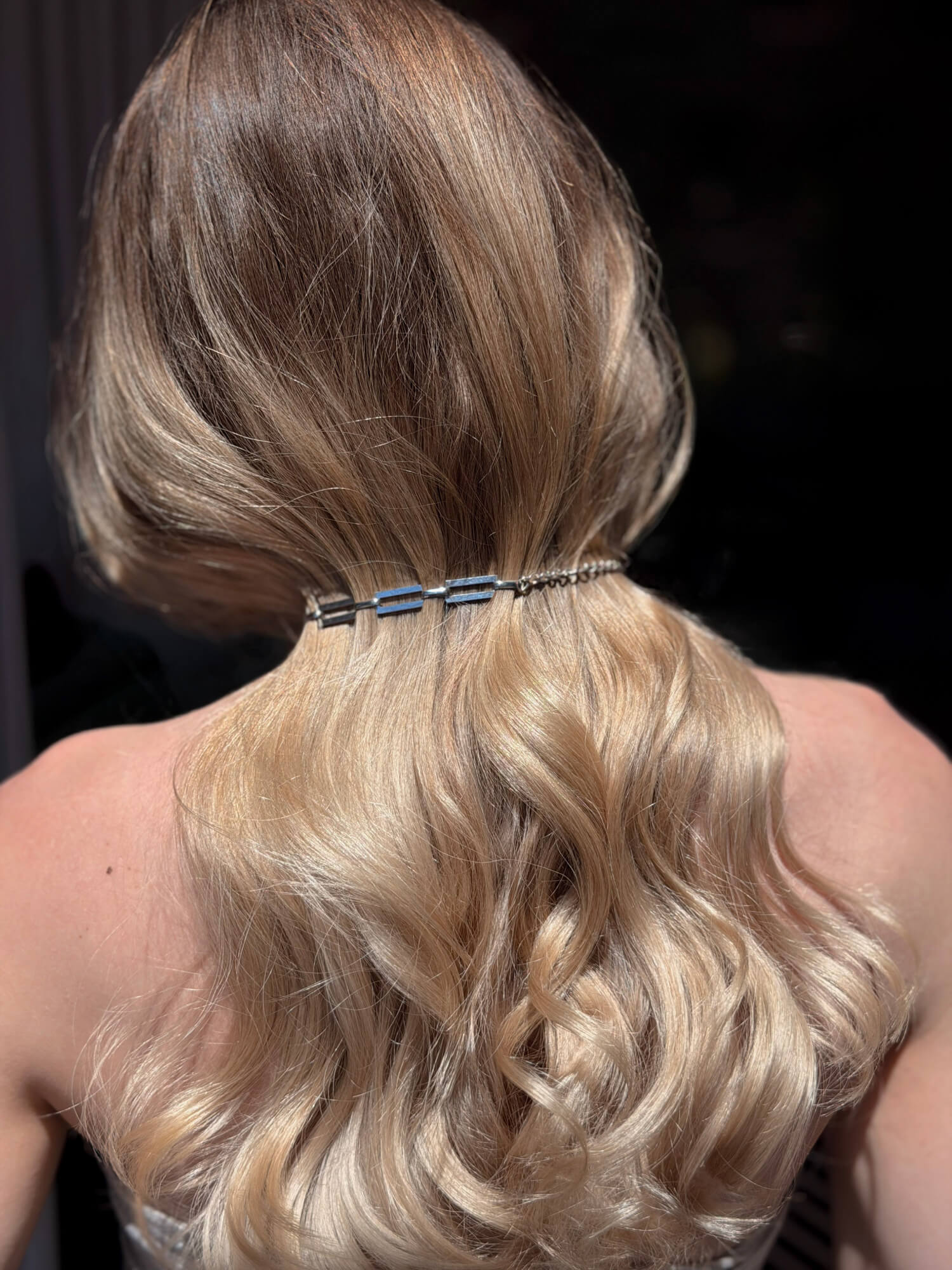 Hair styled in loose waves with a silver link chain necklace 
