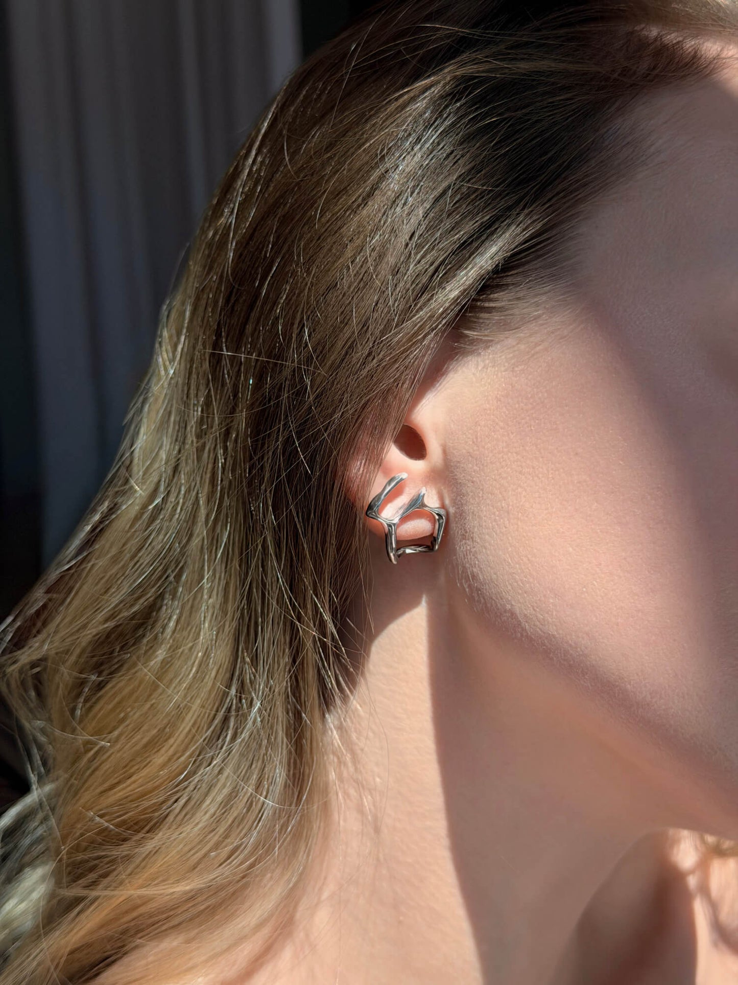 Model wearing fluid form silver earrings