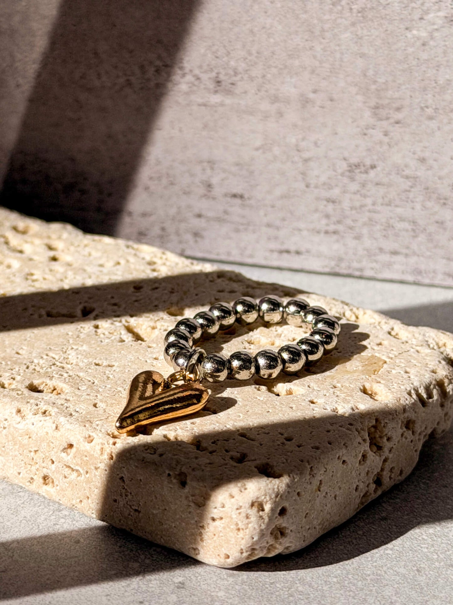 Silver beaded ring with gold heart charm on stone