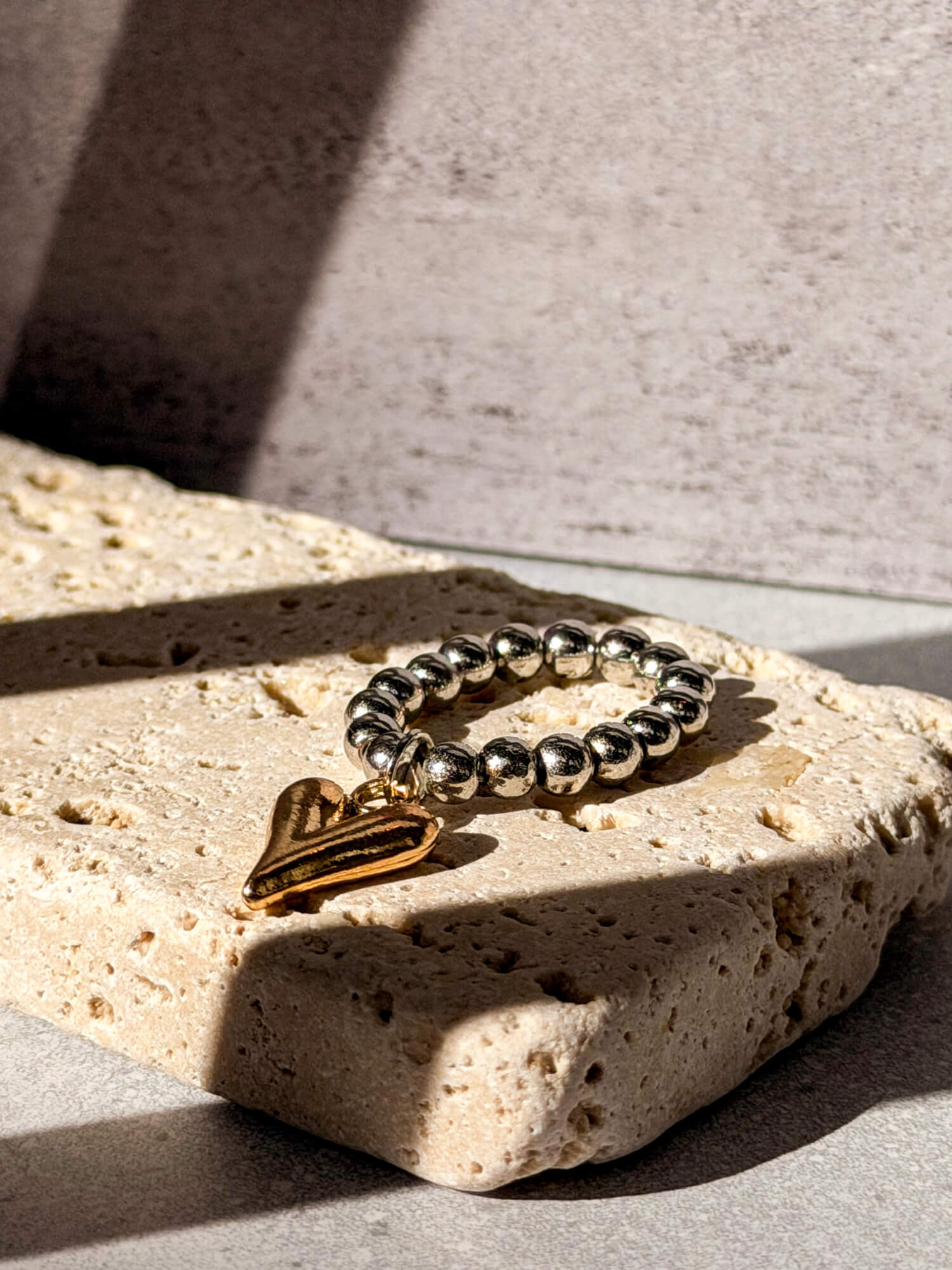 Silver beaded ring with gold heart charm on stone