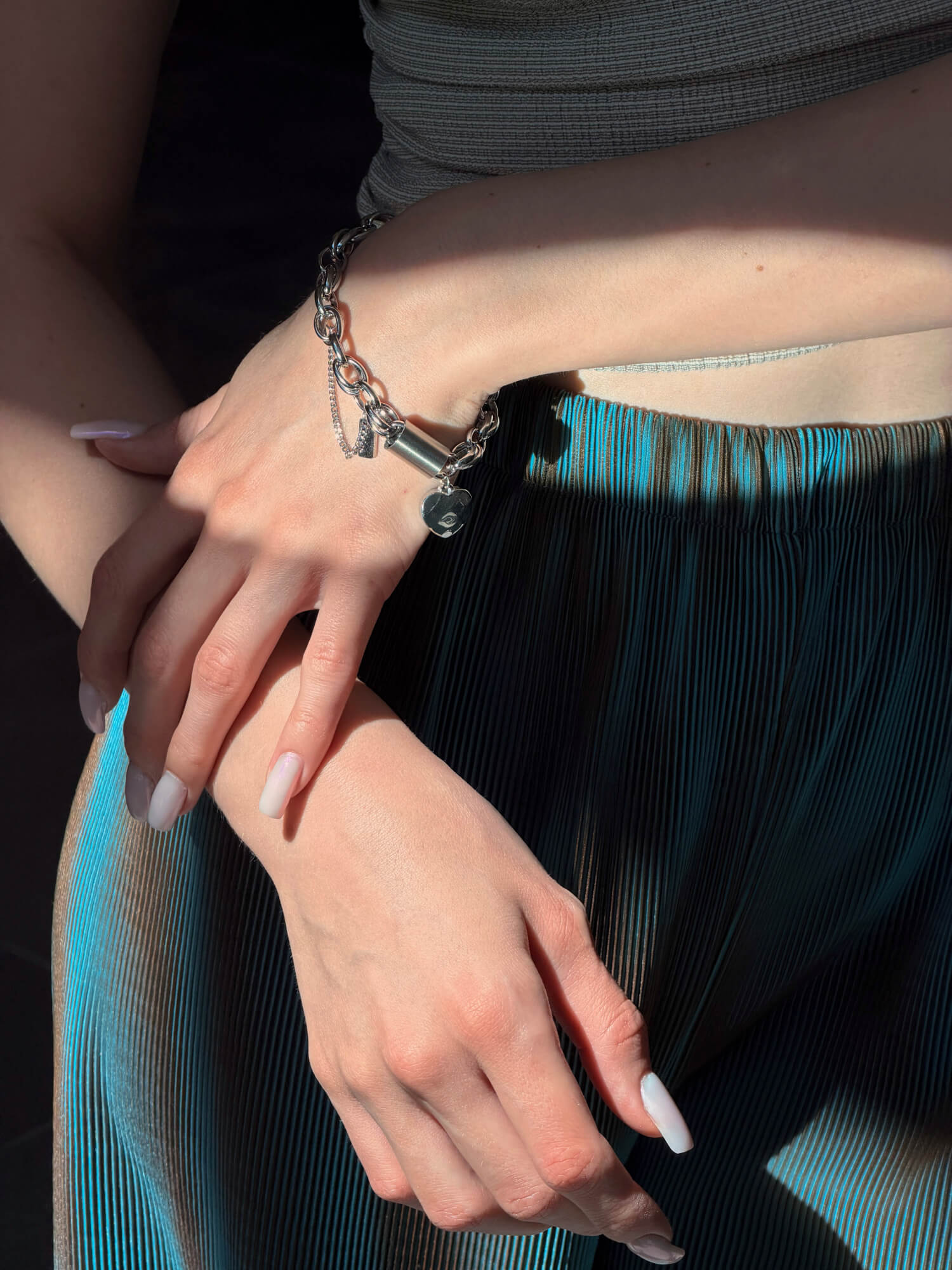Model wearing heart charm silver bracelet on wrist