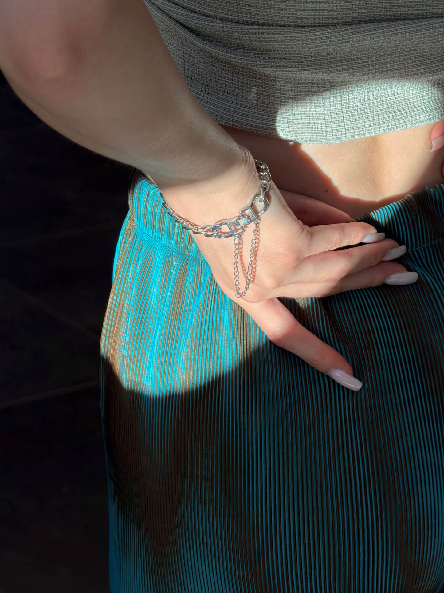 Model wearing layered silver chain bracelet on wrist
