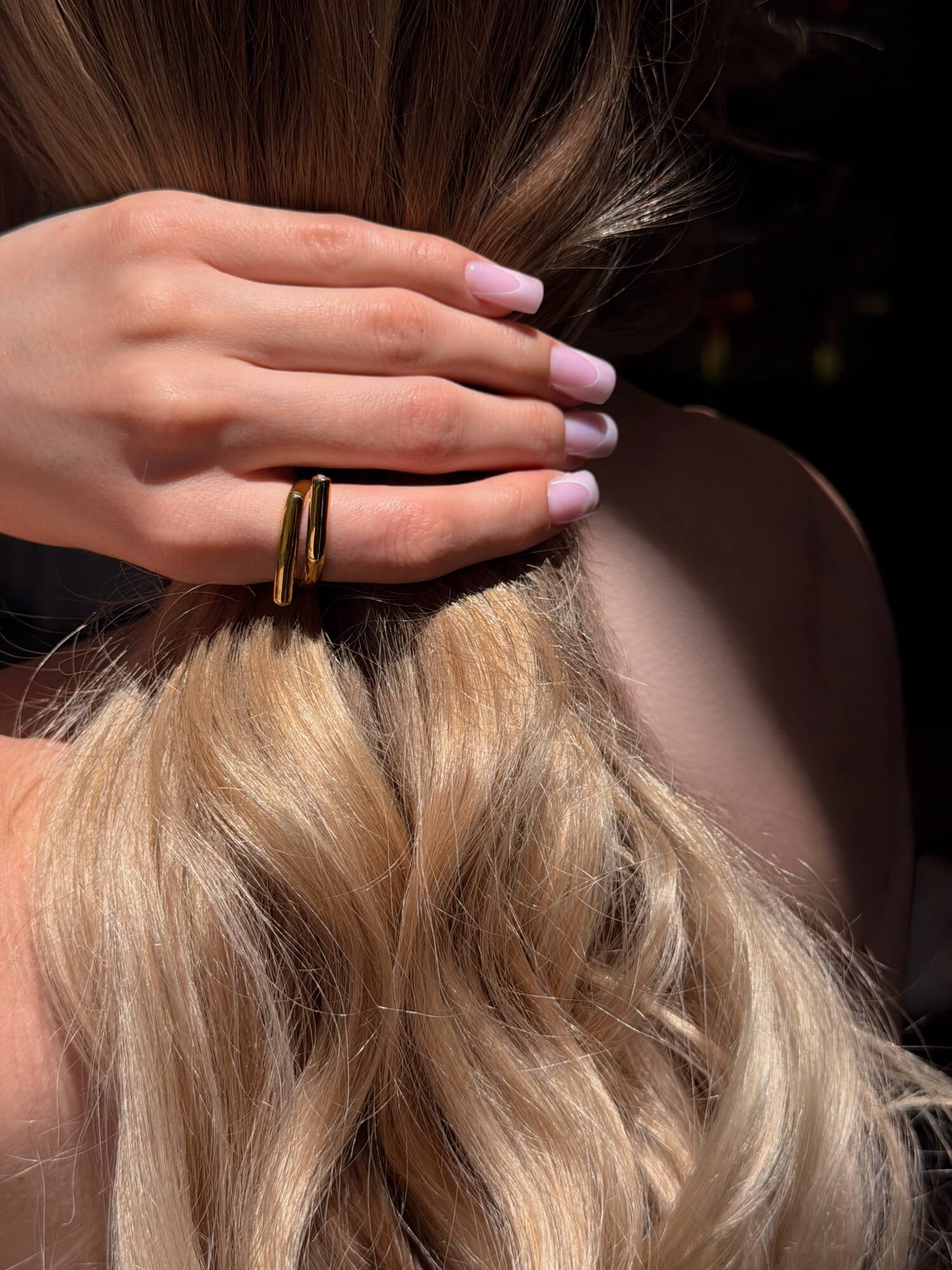 Model wearing sculptural wrap gold ring on finger