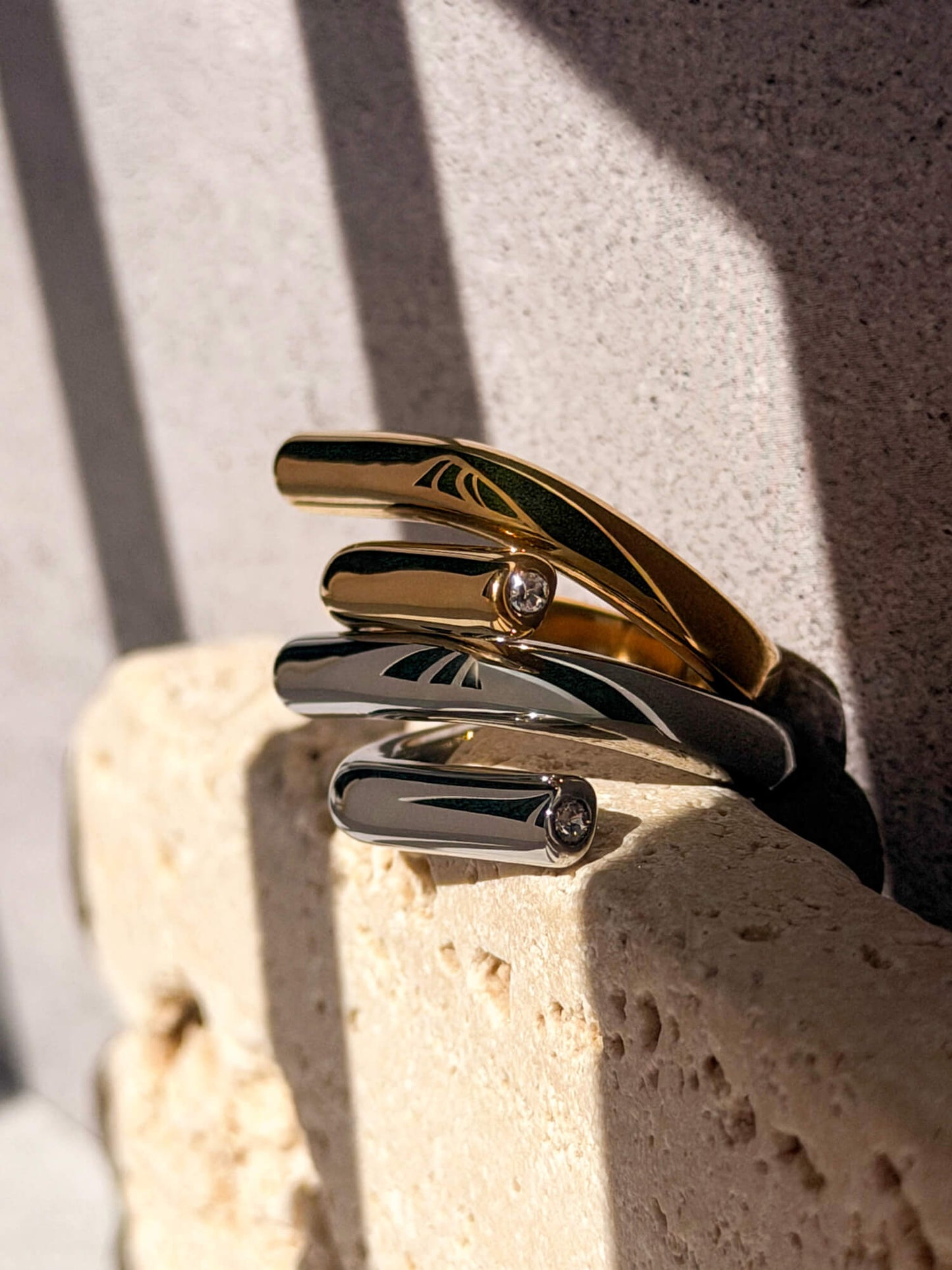 Gold and silver rings with crystal accent detail, sculptural wrap band