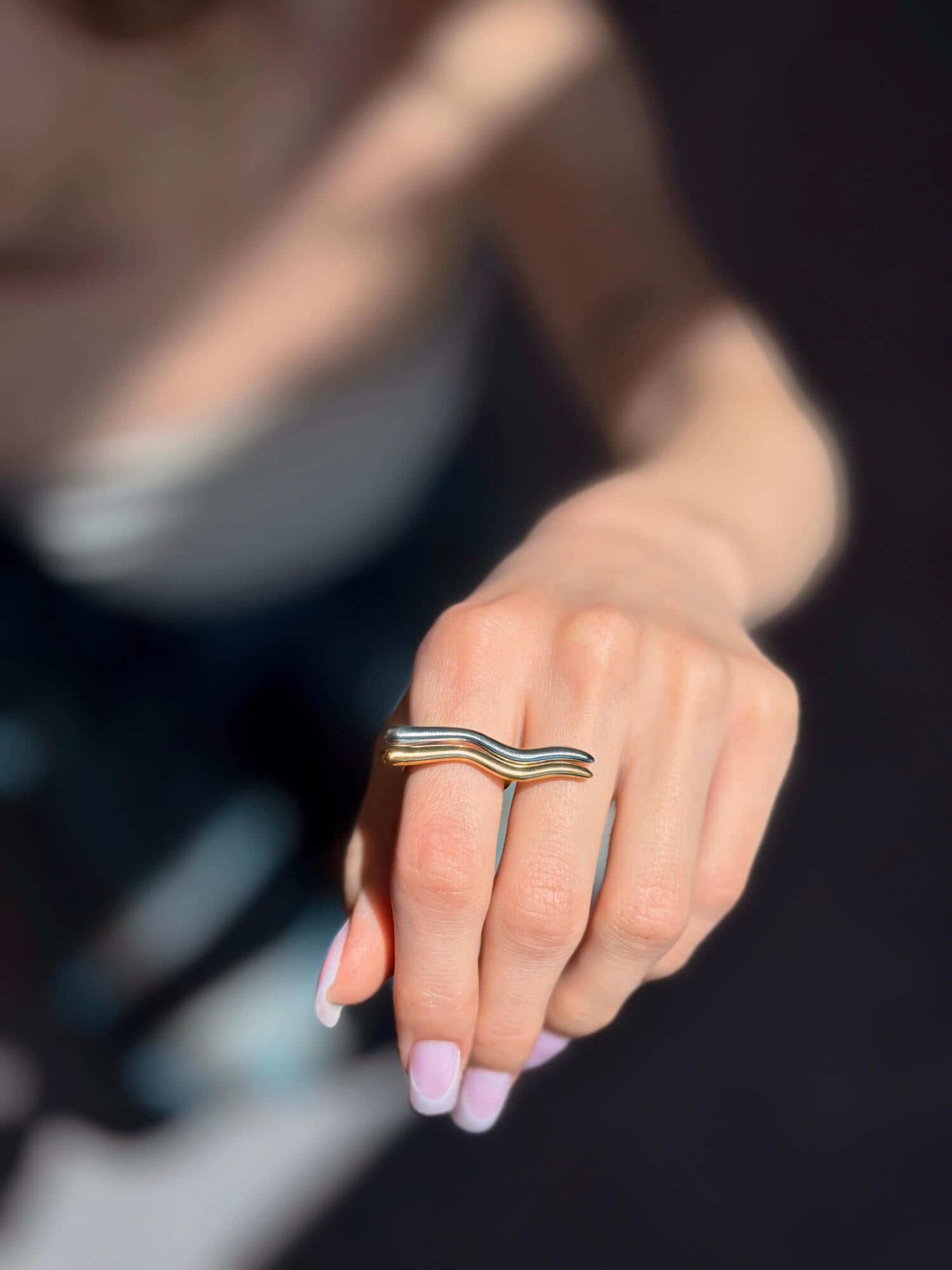 Model wearing wave curve gold and silver rings on finger