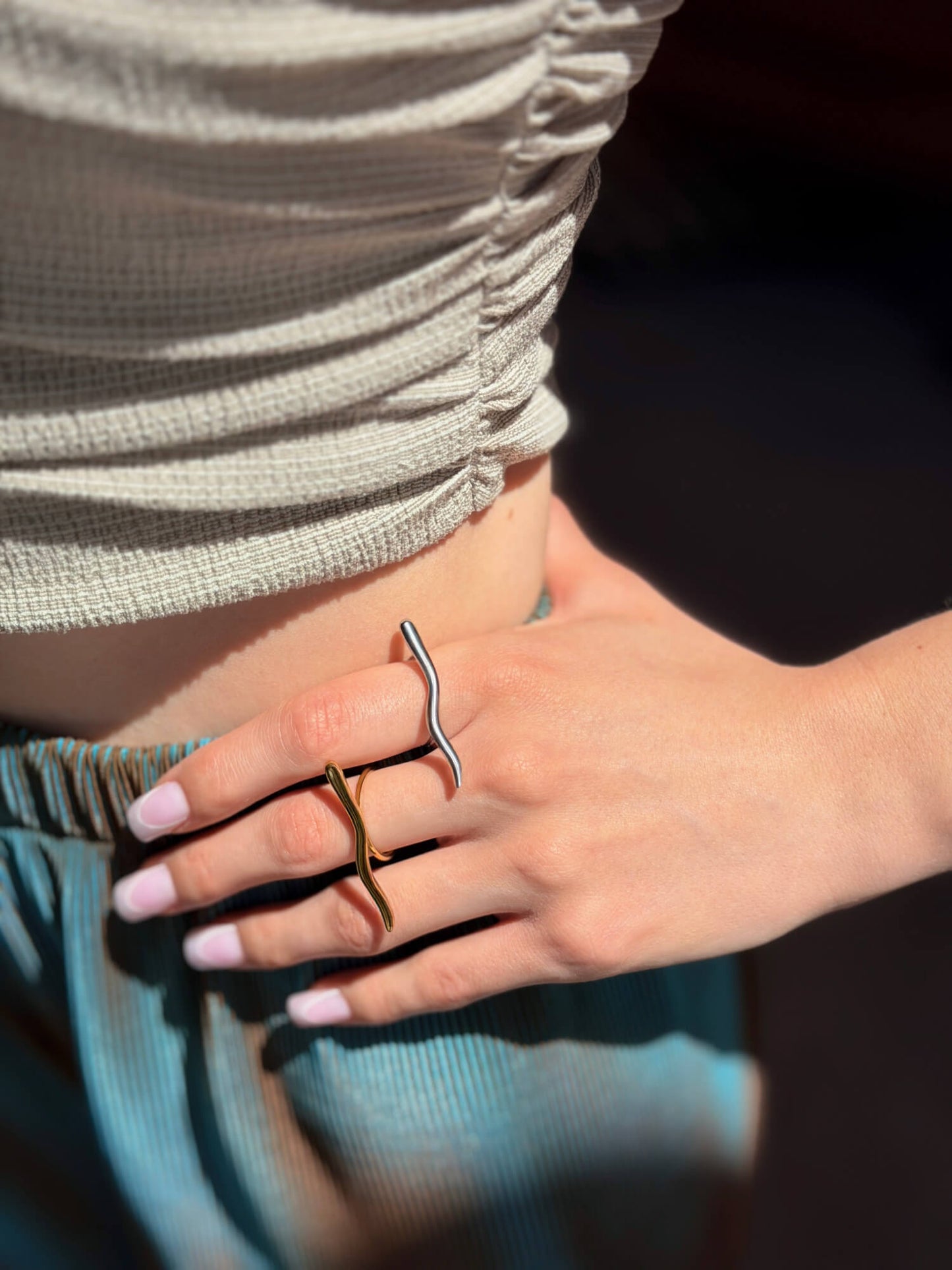 Sculptural gold and silver rings, wave design, on model